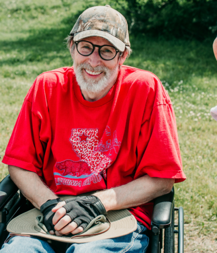 Een meneer in een rolstoel met een petje op