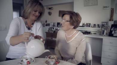 Mevrouw schenkt thee in voor een andere mevrouw