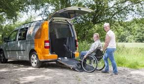 Foto van een rolstoel bus waar een mevrouw in een rolstoel wordt ingerold