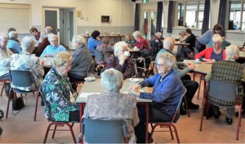 Een groep ouderen die samen in een ruimte zitten