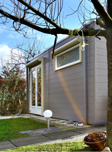 Foto van een huis met een spiegeling van een regenboog op de zijkant.
