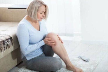 Een vrouw die op de grond zit en last heeft van haar knie